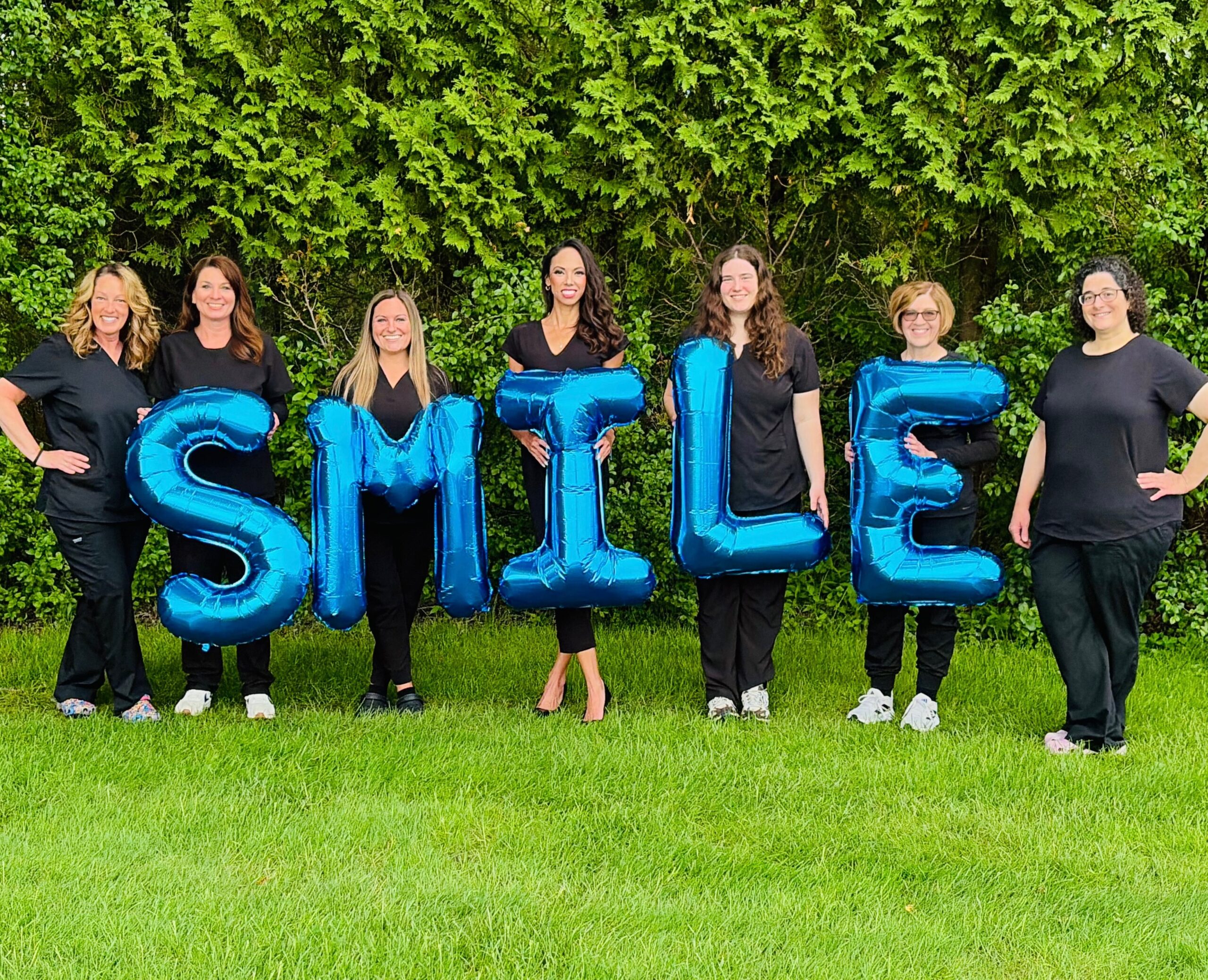 Group of women holding blue "SMILE" balloons